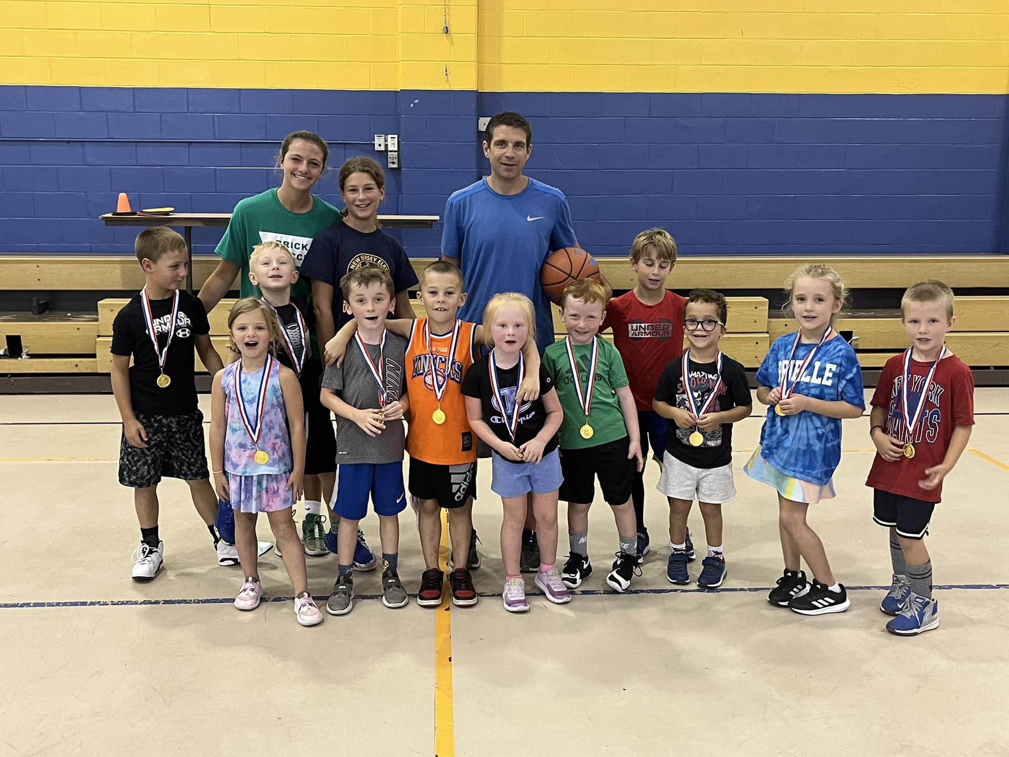 Little Dribblers campers proudly wearing their medals with Coach Nick